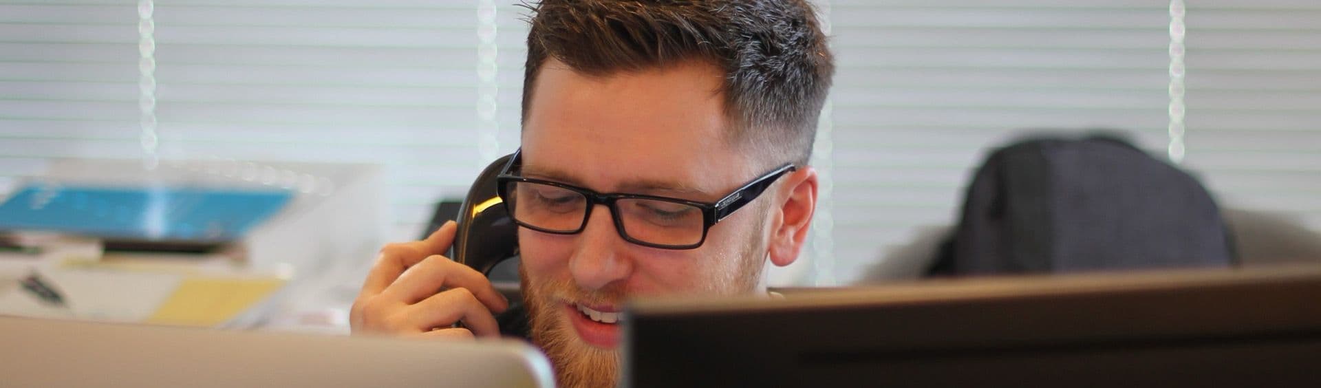 person talking on the phone while looking at a computer screen