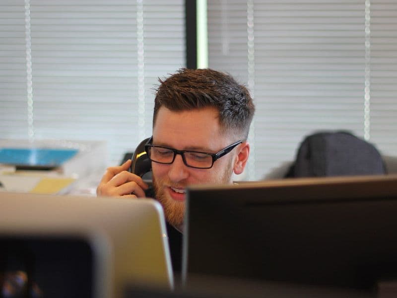 person talking on the phone while looking at a computer screen